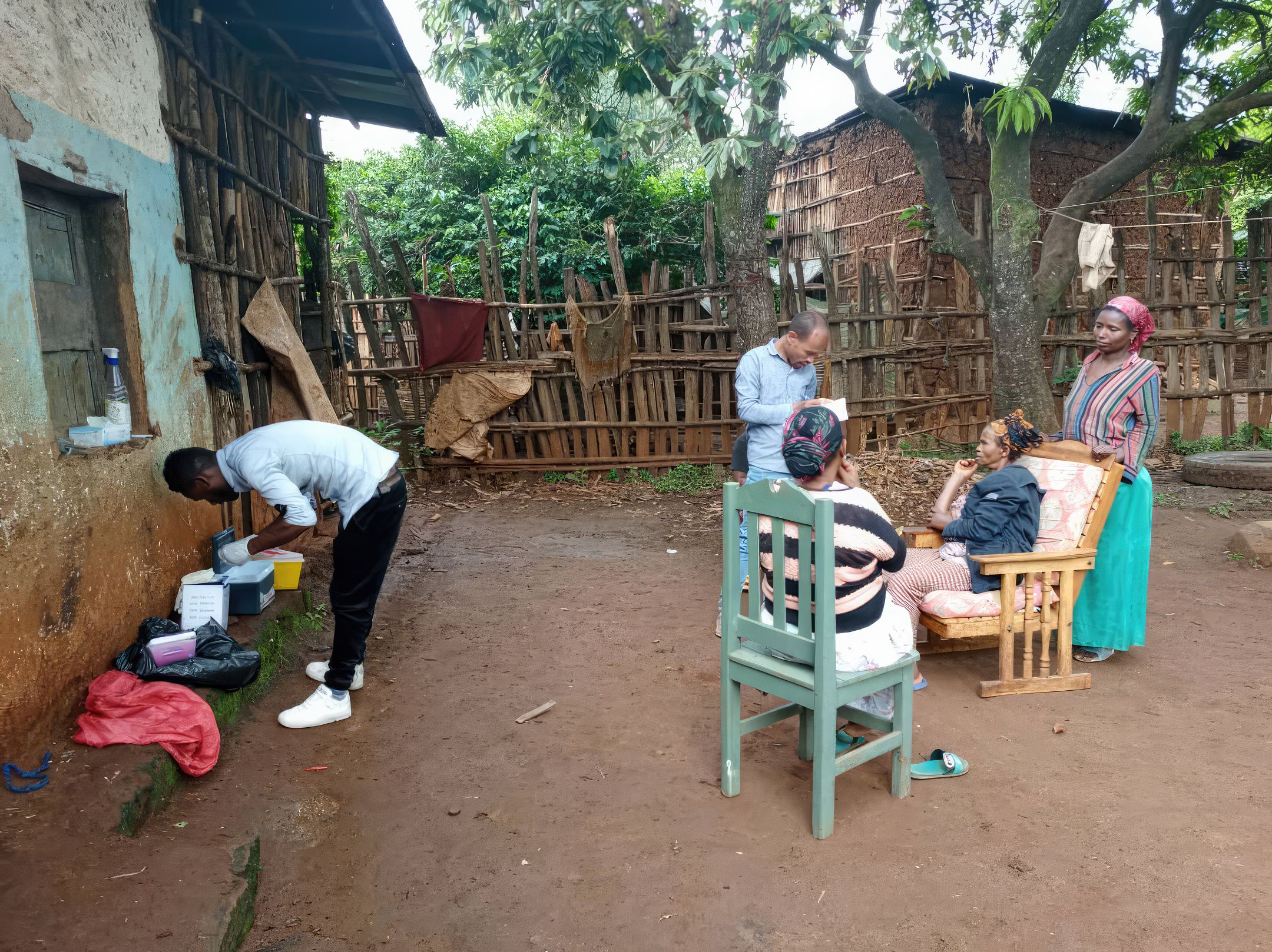 Man holds paperwork standing beside three women as another man stands beside medical equipment outside building