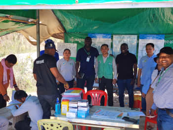 Group of people stand smiling behind a table of equipment