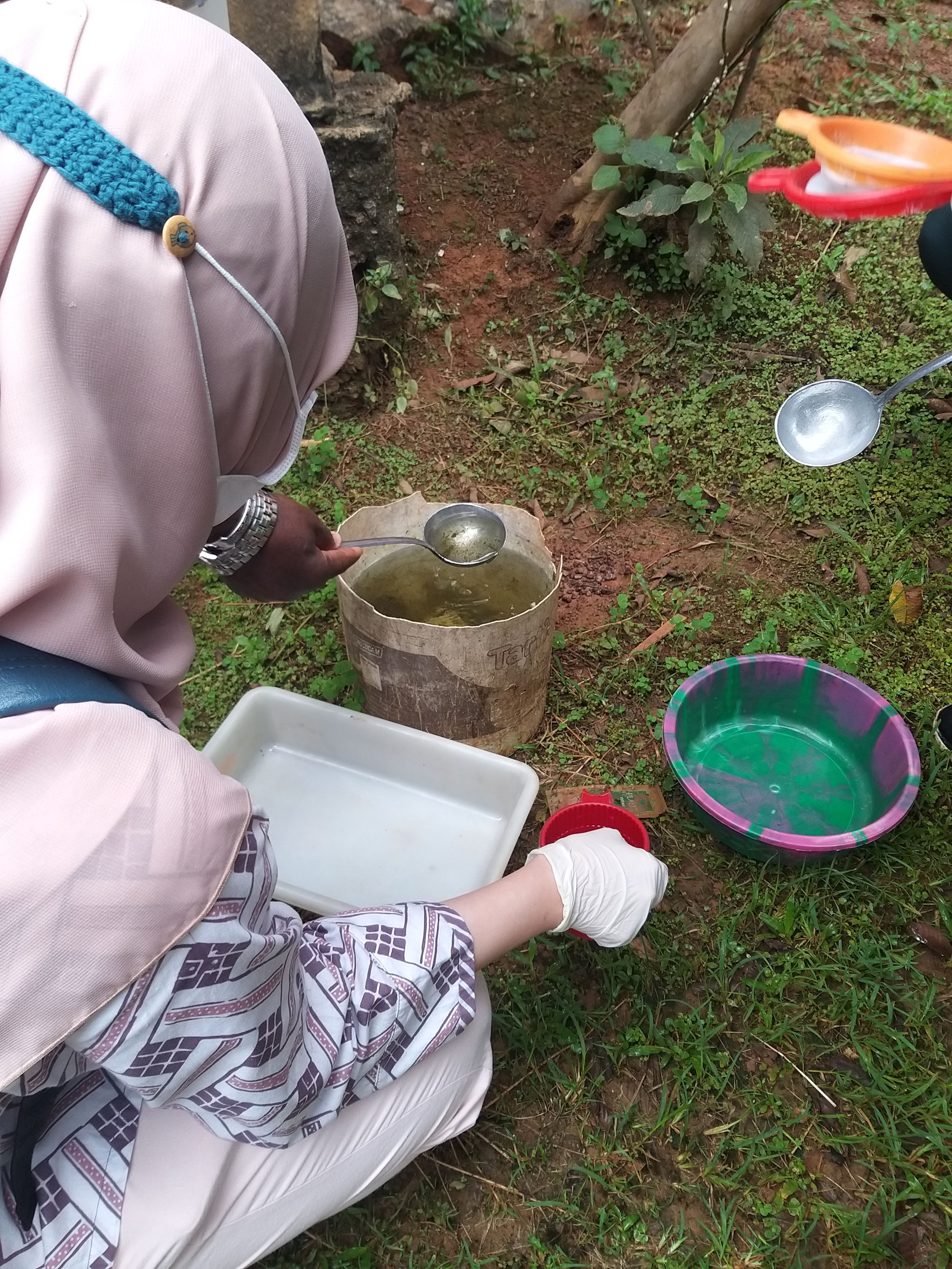Woman crouches beside containers of water
