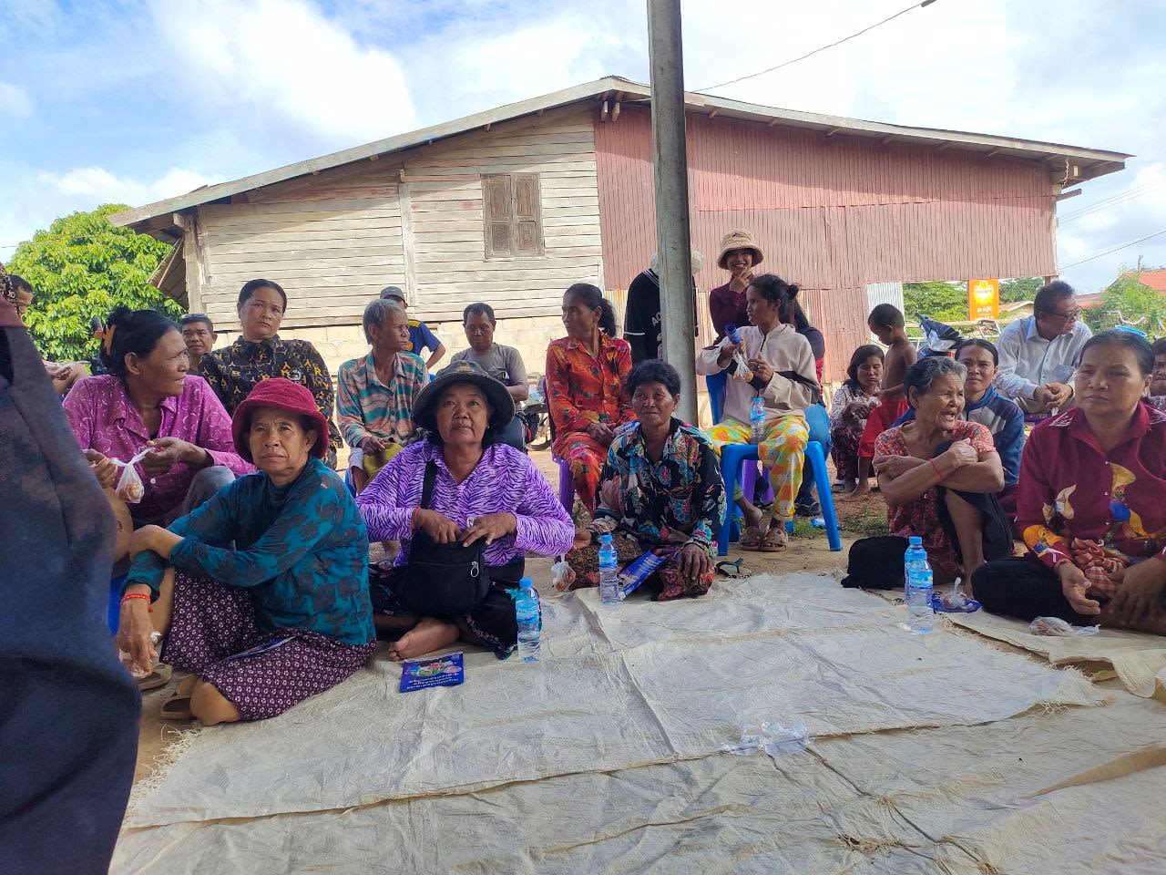 Group of people sit on mats listening to someone speaking