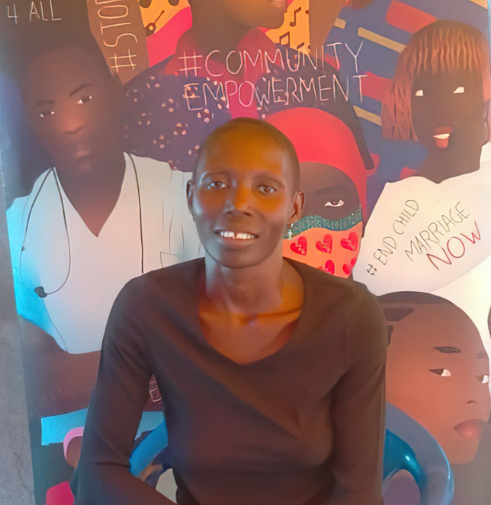 Smiling woman sits in front of brightly painted mural
