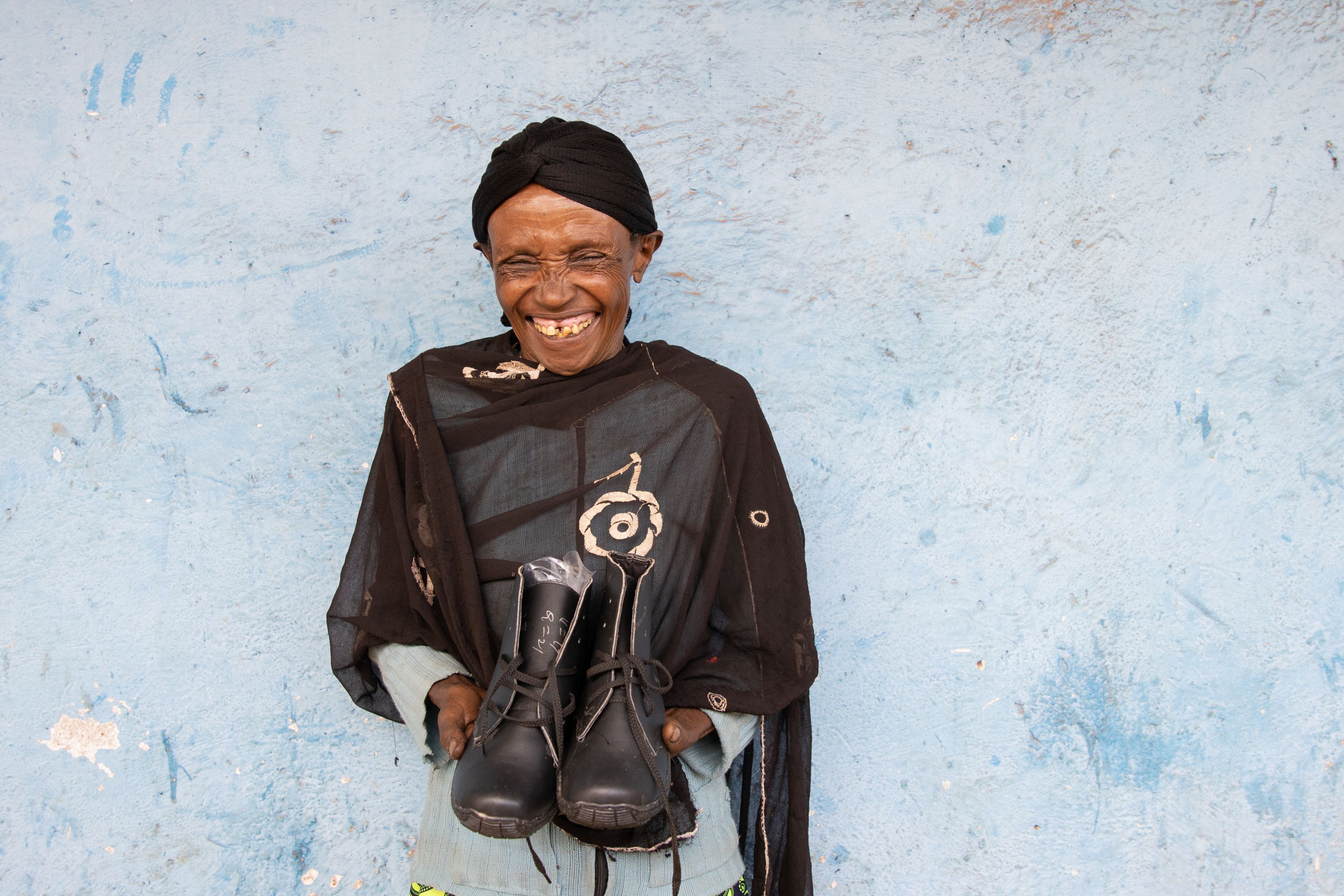 Smiling woman holds a pair of boots