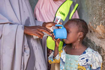 African child drinking medication from a blue cup