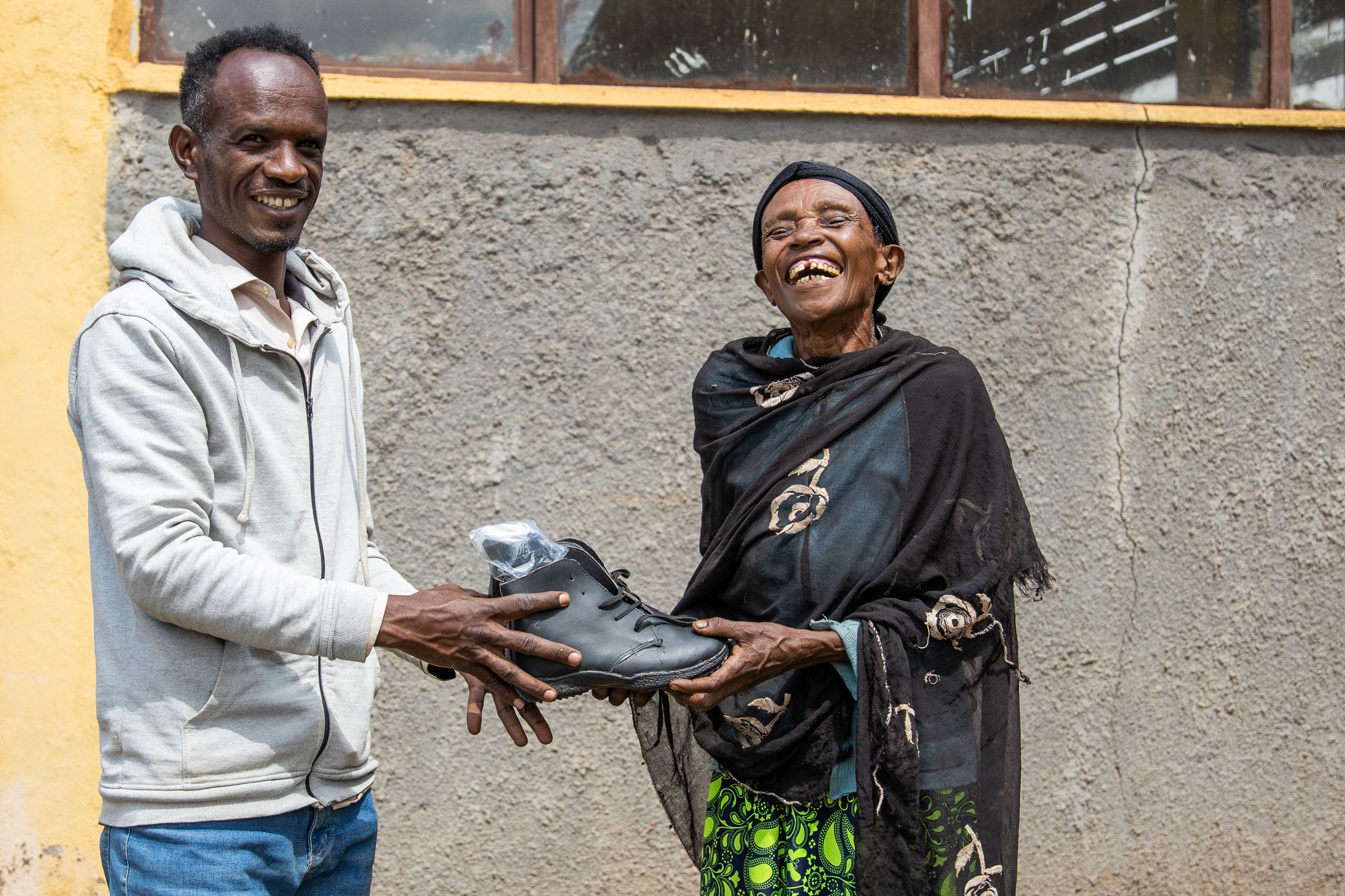Smiling healthcare worker hands boots to laughing woman