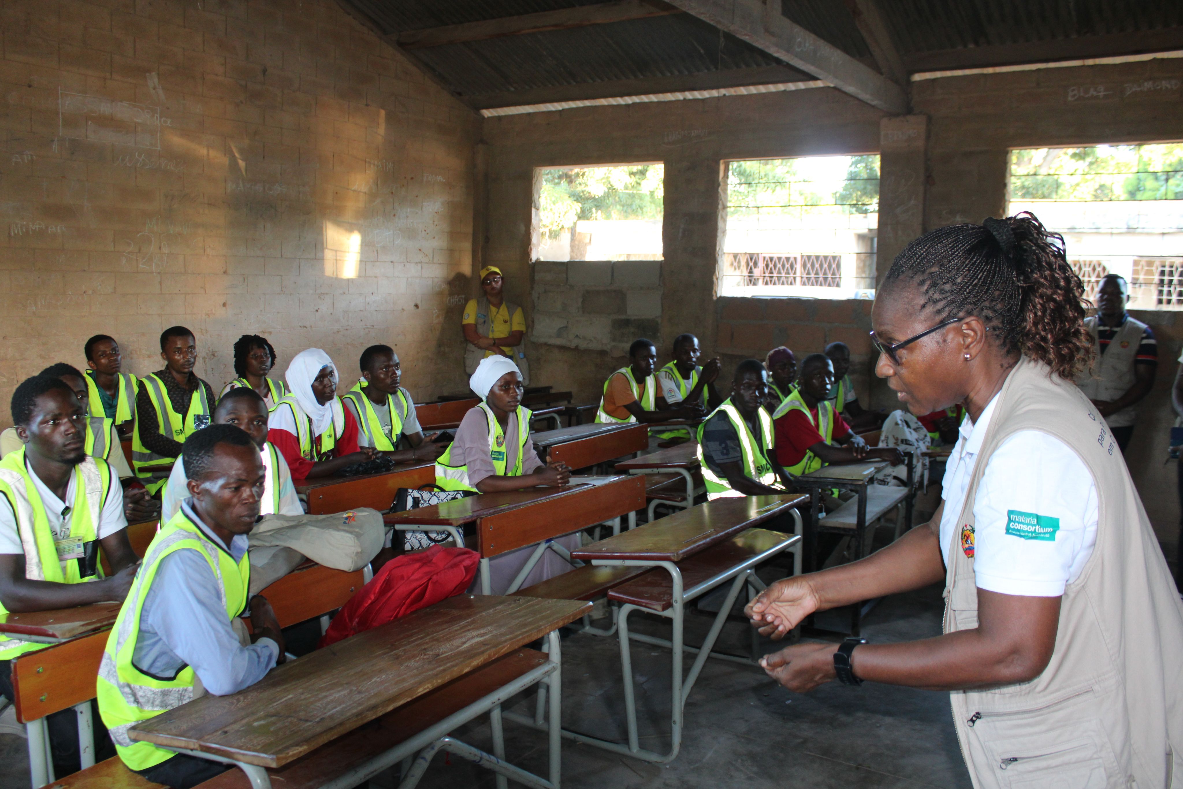Woman speaks to group of community distributors sitting at desks