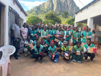 A group of people wearing green tabards hold boxes containing mobile phones