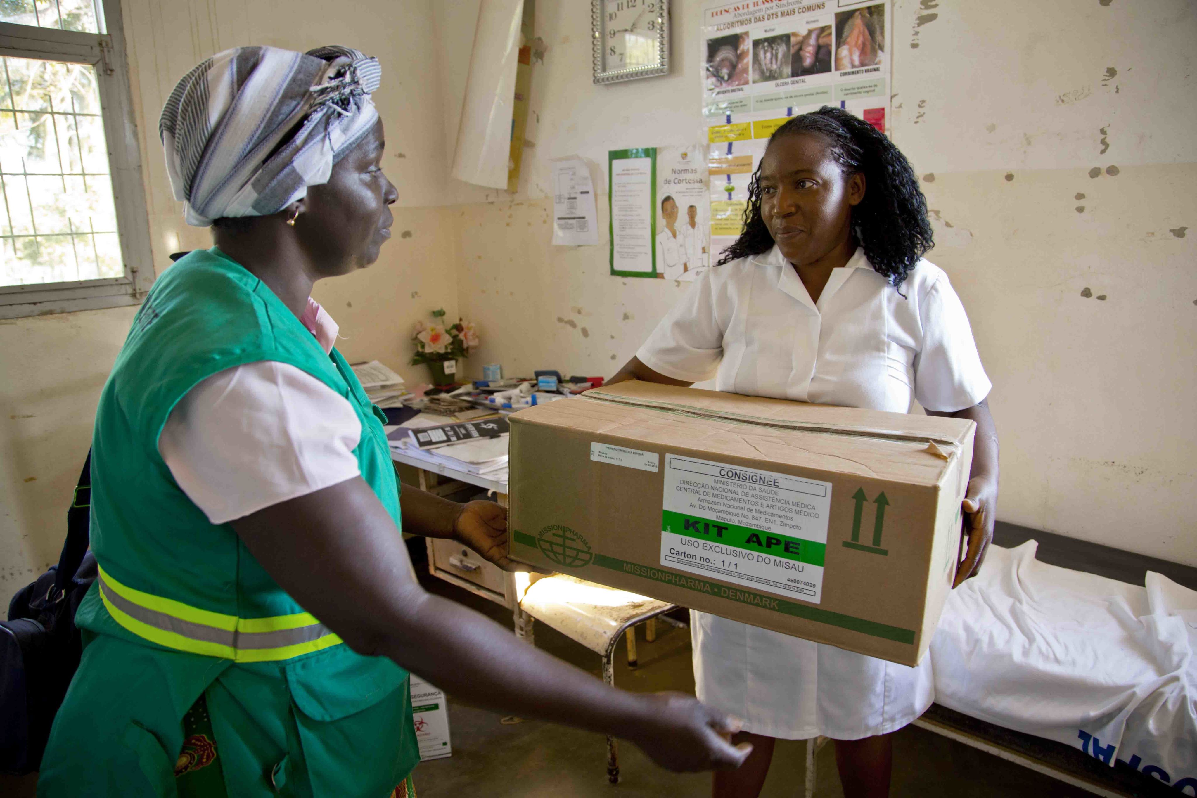 One woman has arms extended to collect a box from the other